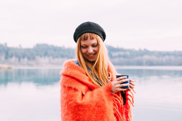 Free photo young woman drinks coffee cup on lake shore