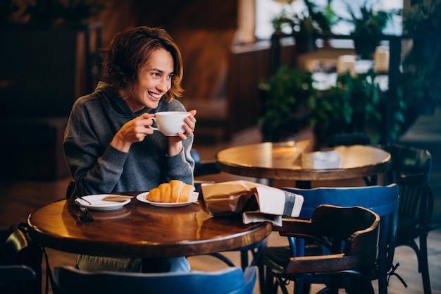 Young woman eating croissants at a cafe