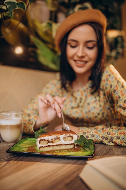 Young woman eating delicious tiramisu in a cafe