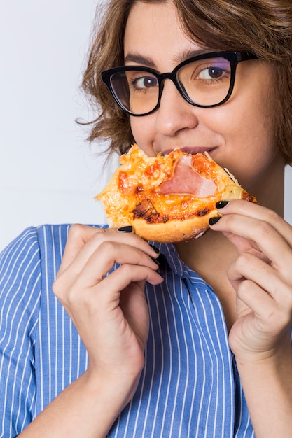 Free photo young woman eating the pizza isolated on white background looking to camera