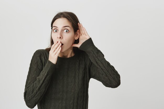 Young woman eavesdropping, gasping as hear shocking gossip