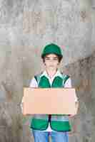 Free photo young woman engineer in green vest and helmet holding paper box