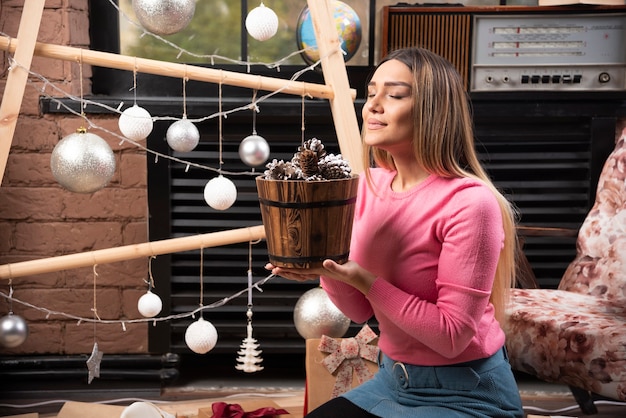 Young woman enjoying bucket of pinecones at home.