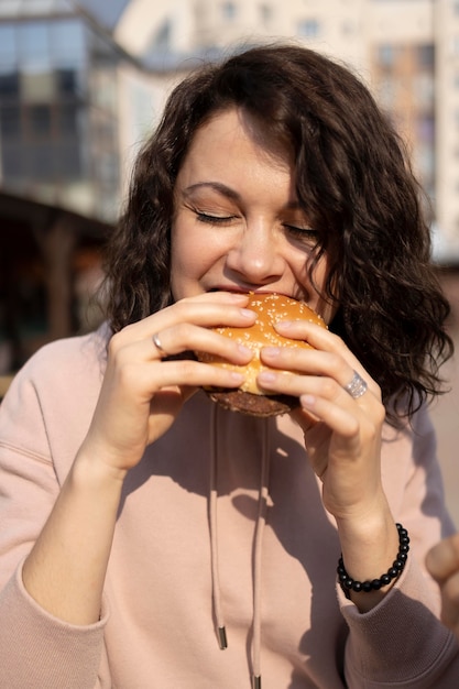 Free photo young woman enjoying some street food outdoors