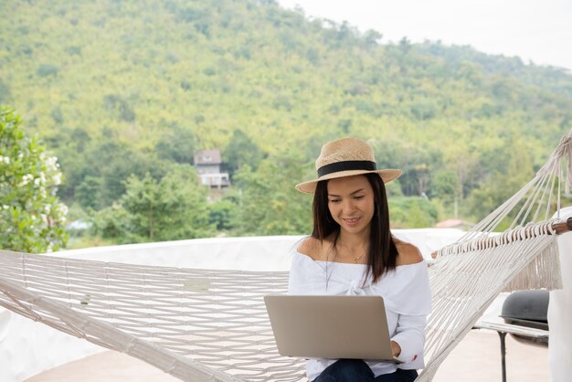 Young woman enjoys a laptop in a hammock on the beach