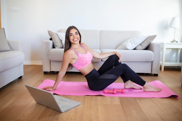 Young woman exercising at home in a living room Video lesson Young woman repeating exercises while watching online workout session Beautiful young woman doing fitness exercise at home