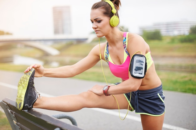 Free photo young woman exercising outdoor. do stretching to avoid some injury