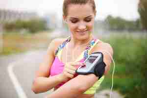 Free photo young woman exercising outside. turning on a playlist before the jogging