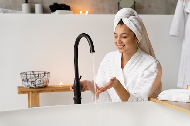 Young woman filling the bathtub and preparing to take a bath