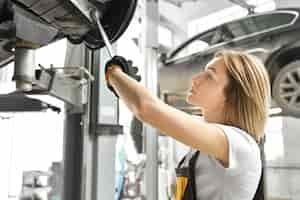 Free photo young woman fixing car undercarriage in autoservice.