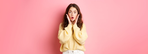 Free Photo young woman gasping and saying wow looking surprised at camera checking out promotion staring at promo offer standing against pink background