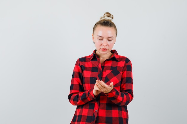 Free Photo young woman gesturing like using mobile phone in checked shirt and looking busy