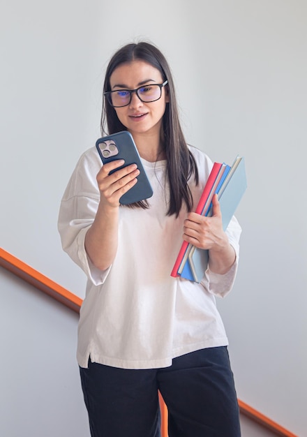 Free Photo young woman in glasses with smartphone and notepads