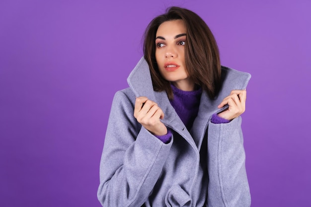 Free Photo young woman in a gray coat on a purple background posing, cozy and warm, autumn winter style