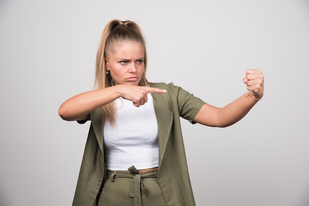 Free photo young woman in green jacket pointing at something.