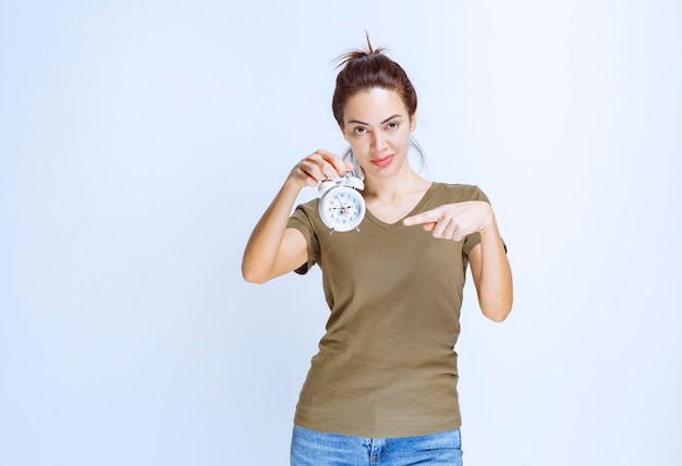 Young woman in green shirt holding an alarm clock