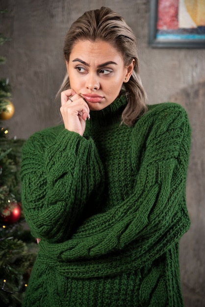 Free photo young woman in green sweater looking away and posing