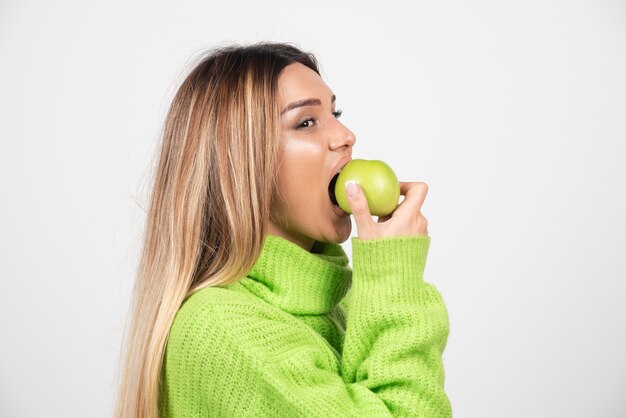 Young woman in green t-shirt eating an apple