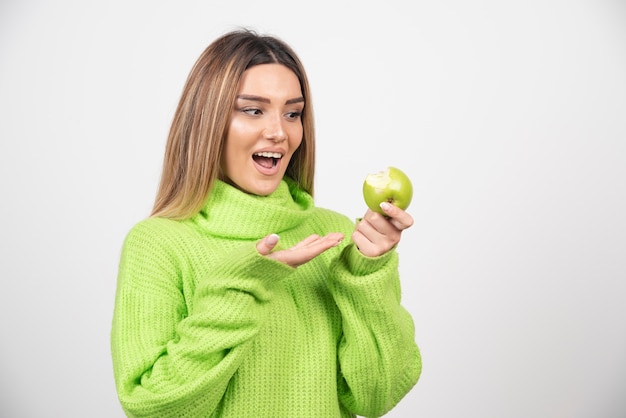 Free photo young woman in green t-shirt holding an apple