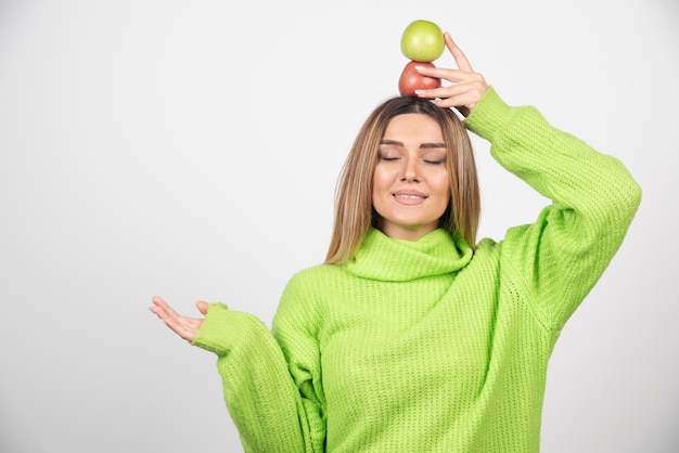 Free photo young woman in green t-shirt holding two apples overhead