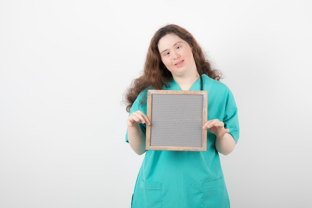 young woman in green uniform holding a frame.