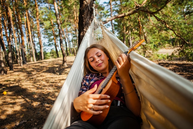 Young woman in hammock playing quitar