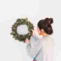 Free photo young woman hanging christmas wreath