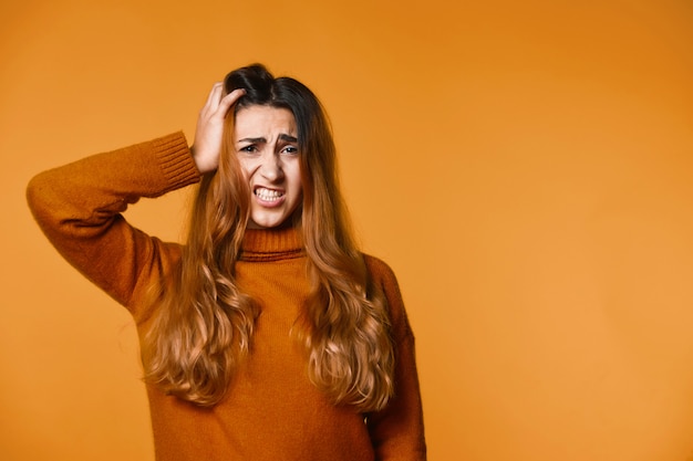 Young woman has worried look and holds one hand on to her head