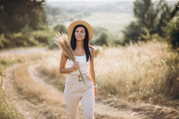 Young woman in a hat in a field of wheat