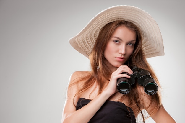 Young woman in hat with binoculars