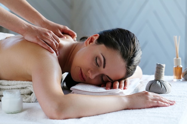 Free photo young woman having back and shoulder massage