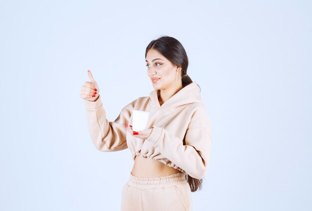 Young woman having a cup of coffee and showing enjoyment sign