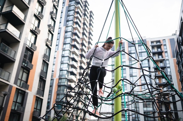 Free photo young woman having fun on the rope pyramid