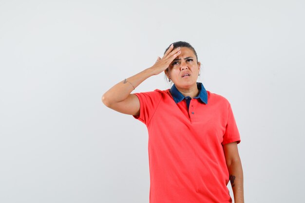 Young woman having headache in red t-shirt and glasses and looking pensive. front view.