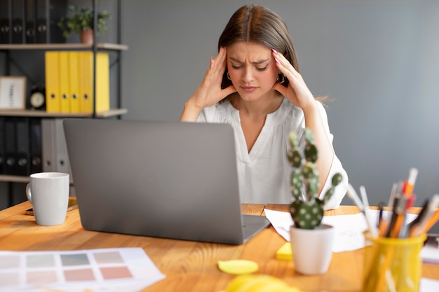 Young woman having a headache at work