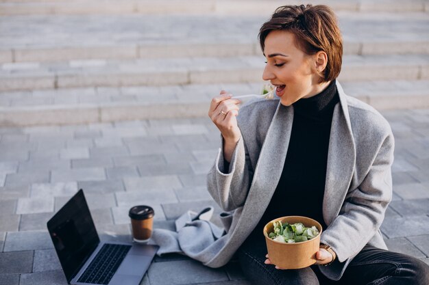 Young woman having lunch and working online