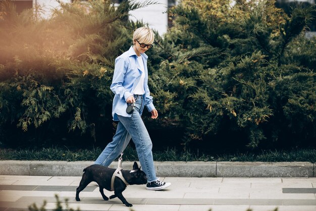 Free Photo young woman having a walk with her pet french bulldog