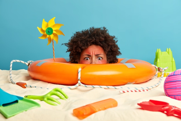 Free photo young woman head with sunscreen cream on face surrounded by beach accessories