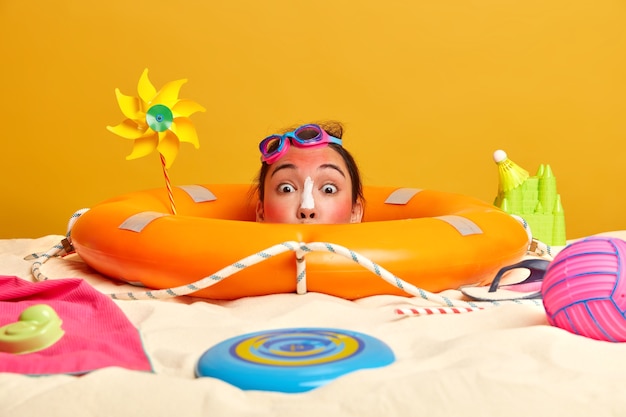 Free photo young woman head with sunscreen cream on face surrounded by beach accessories