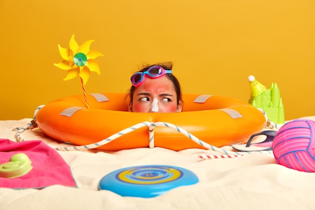 Free Photo young woman head with sunscreen cream on face surrounded by beach accessories