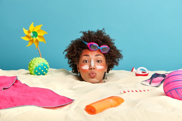 Free Photo young woman head with sunscreen cream on face surrounded by beach accessories