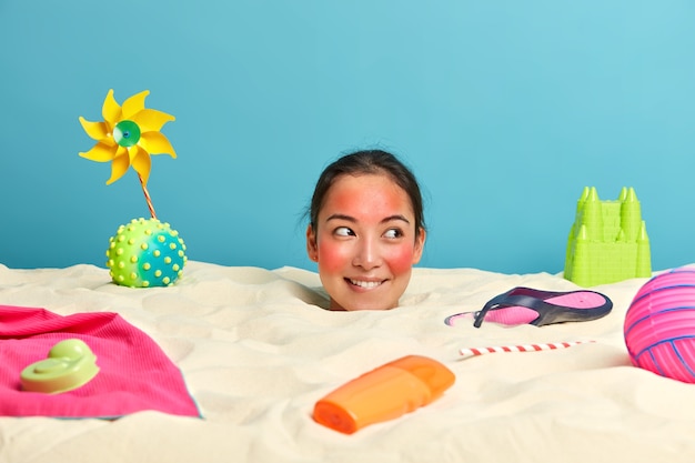 Free Photo young woman head with sunscreen cream on face surrounded by beach accessories