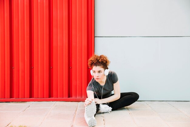 Young woman in headphones doing stretching exercises