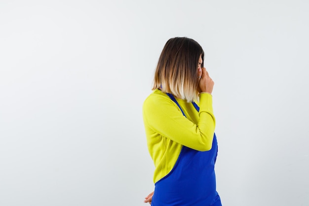 Young woman hiding her face with hands and turning to the back on white background