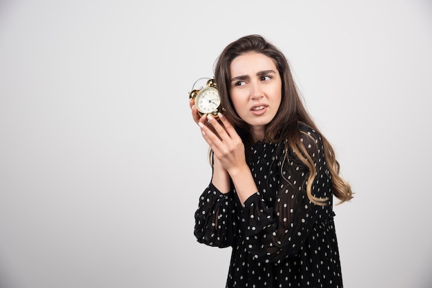 Young woman holding an alarm clock 