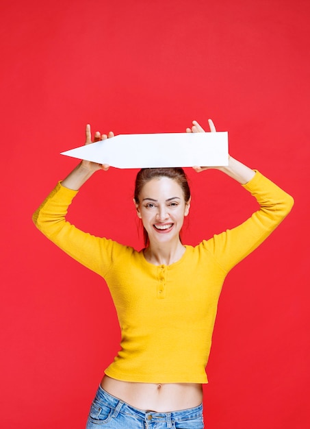 Free photo young woman holding an arrow pointing to the left