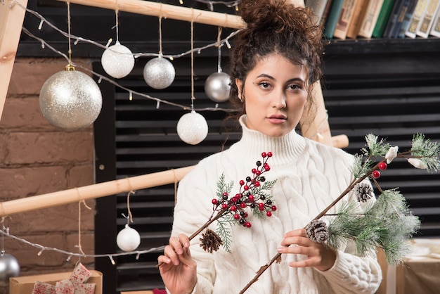 Free photo young woman holding a branch of christmas holly berry