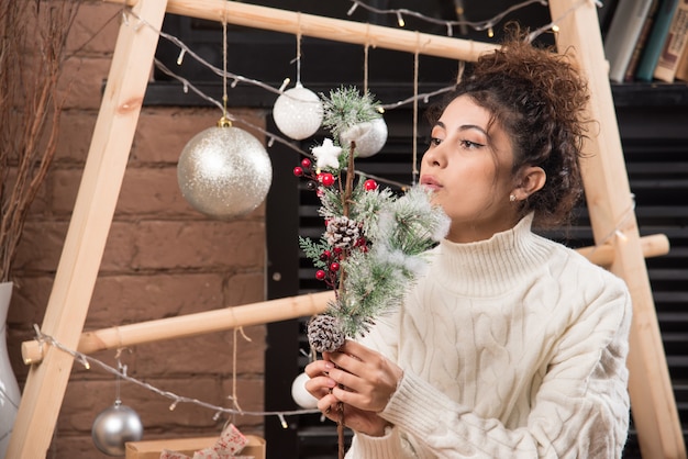 Free photo young woman holding a branch of christmas holly berry