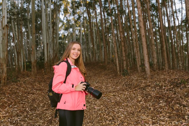 Young woman holding camera in forest