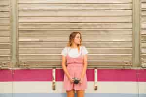 Free photo young woman holding camera in hand looking away